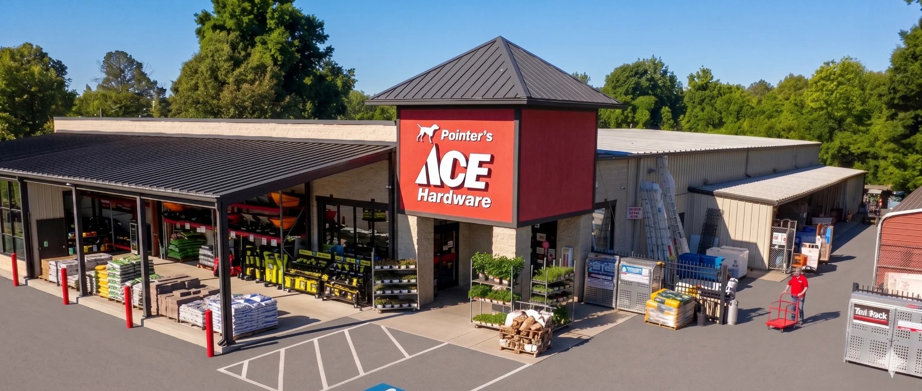 Exterior view of Donners Ace Hardware store with red central tower, covered entrance area, and merchandise displays on a sunny day