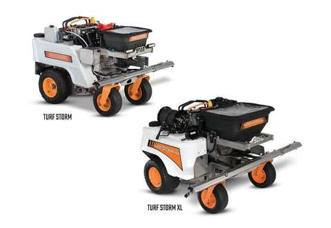 Two white and orange Turf Storm lawn rollers with black hoppers and wheels on white background